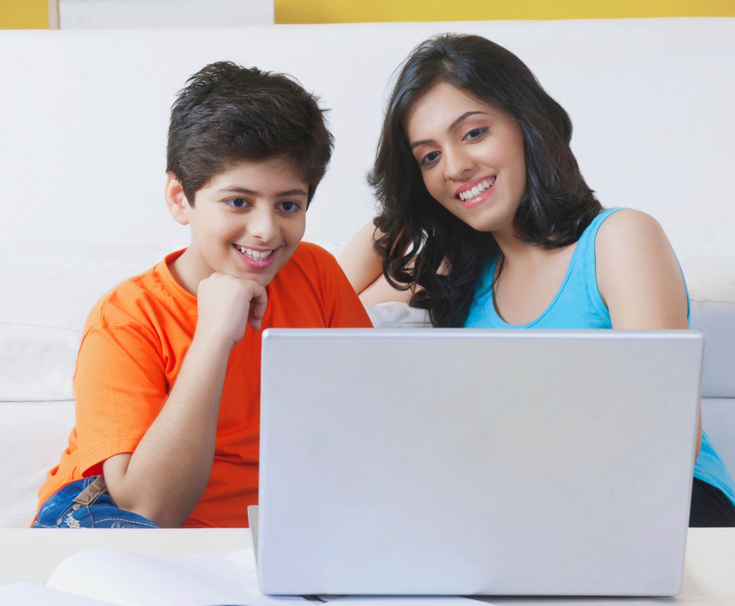 Mother and primary school student looking at a laptop screen smiling at their online tutor.